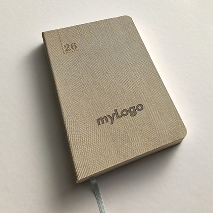 Ημερολόγιο Ατζέντα Tailor Made 3570 με χάραξη Laser												Σχήμα 14x21 εκ.								Μπεζ								Εύκαμπτη βιβλιοδεσία								Πυρογραφικό υλικό με tweed μοτίβο								Στρογγυλές γωνίες								Λάστιχο 				Στο εξώφυλλο του ημερολογίου μπορεί να χαραχτεί το λογότυπο σας.Η χάραξη γίνεται με χρήση laser που αποδίδει όσο το δυνατό καλύτερα τα λογότυπα.				Τα ημερολόγια που παρουσιάζουμε είναι ενδεικτικά και προσφέρονται ανάλογα τη διαθεσιμότητα. Το τελικό αποτέλεσμα ενδέχεται να διαφέρει ανά περίπτωση Επικοινωνήστε μαζί μας για να βρούμε μαζί το ημερολόγιο που θέλετε.    