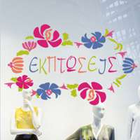 Αυτοκόλλητο βιτρίνας από βινύλιο που απεικονίζει μια μπορντούρα με λουλούδια σε οπάλ χρώματα, γύρω από τη λέξη 
